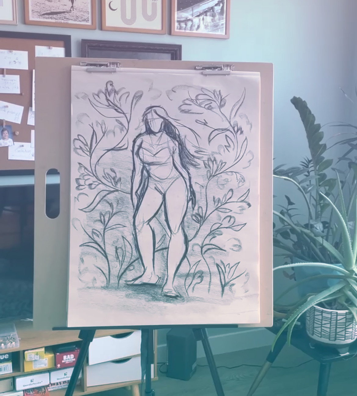 A newsprint pad on an easel with loose charcoal gesture lines in lamp light